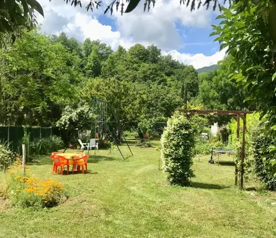 a garden with a table and chairs and a swing at chambre et salle de bain privé s'ouvrant sur terrasse, jardin et cuisine d'été in Quillan