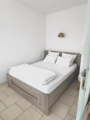 a bed with white sheets and pillows in a room at Plage des Chalets appartement T2+terrasse in Gruissan