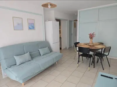 a living room with a blue couch and a table at Plage des Chalets appartement T2+terrasse in Gruissan
