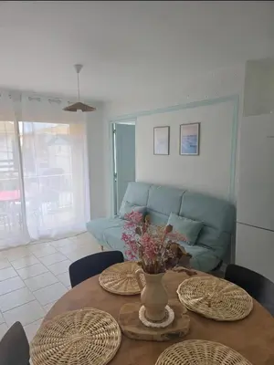 a living room with a table and a couch at Plage des Chalets appartement T2+terrasse in Gruissan