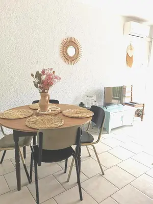 a dining room table with chairs and a vase with flowers at Plage des Chalets appartement T2+terrasse in Gruissan