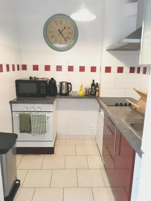 a kitchen with a clock on the wall and a stove at Plage des Chalets appartement T2+terrasse in Gruissan