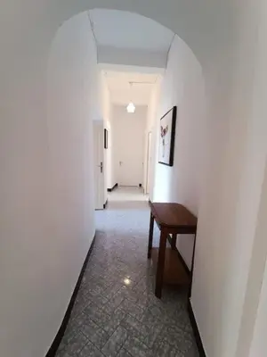 a hallway with a wooden table and a white wall at Maison de village 8 couchages in La Livinière