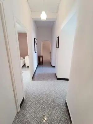a hallway with white walls and a room with a table at Maison de village 8 couchages in La Livinière