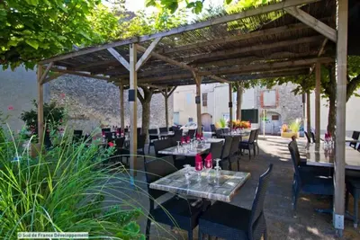 a restaurant with tables and chairs under a pergola at Maison de village 8 couchages in La Livinière