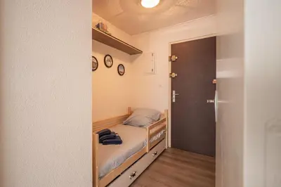 a small bedroom with a bed and a closet at L'Escale de la Plage in Gruissan