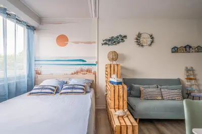 a bedroom with a bed and a couch at L'Escale de la Plage in Gruissan