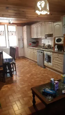 a kitchen with white cabinets and a wooden floor at Maison proche de la nature in Quérigut