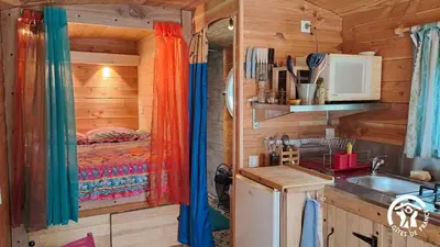 a kitchen with a sink and a bed in a log cabin at Terra bosca roulotte in Cambounès