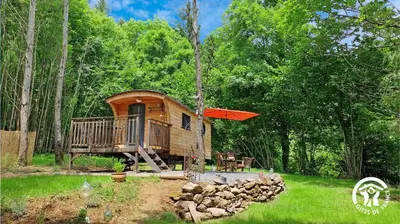 a cabin in the woods with a porch and a deck at Terra bosca roulotte in Cambounès