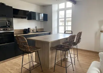 a kitchen with a island with bar stools at White Wood in Narbonne