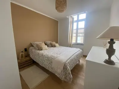 a bedroom with a bed and a lamp and a window at White Wood in Narbonne