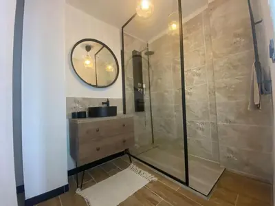 a bathroom with a shower with a sink and a mirror at White Wood in Narbonne