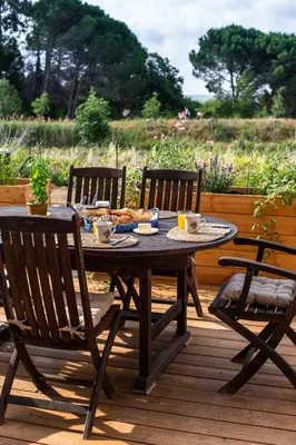 a wooden table and chairs on a deck at Maison avec piscine, vue sur le Canal du Midi in Capestang