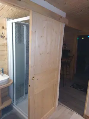 a wooden door in a bathroom with a shower at LOU CABANOT CHALET DE JARDIN CALME ET CONFORTABLE in Lastours
