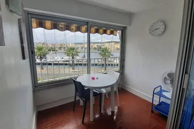 a table and chairs in a room with a large window at Appart. calme 5 Pers vue sur le port de gruissan in Gruissan