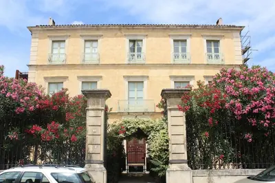 a building with pink flowers in front of it at 2 bedroom home with shared pool in lovely market town of Olonzac in wine region in Olonzac