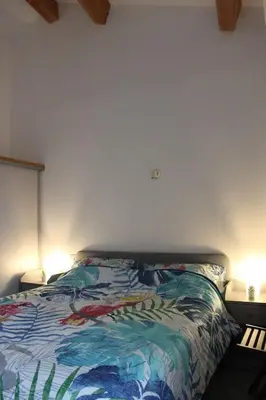 a bed with a colorful comforter and two lamps at 2 bedroom home with shared pool in lovely market town of Olonzac in wine region in Olonzac