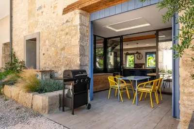 an outdoor patio with yellow chairs and a grill at La Remise des Amis - Proche du centre du village in Peyriac-de-Mer