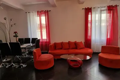 a living room with a red couch and chairs and a table at L'oiseau du paradis in Narbonne
