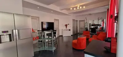 a kitchen and living room with red chairs and a table at L'oiseau du paradis in Narbonne