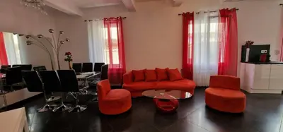 a living room with a red couch and chairs at L'oiseau du paradis in Narbonne
