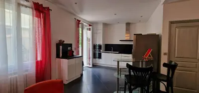a kitchen with a glass table and red curtains at L'oiseau du paradis in Narbonne