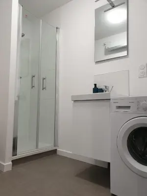 a white bathroom with a shower and a washing machine at Le Jungle in Pamiers