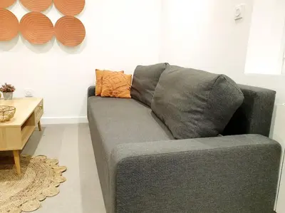 a gray couch with an orange pillow in a living room at Le Bohème in Pamiers