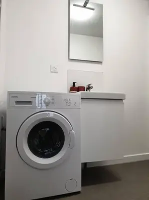 a washing machine in a white room with a mirror at Le Bohème in Pamiers