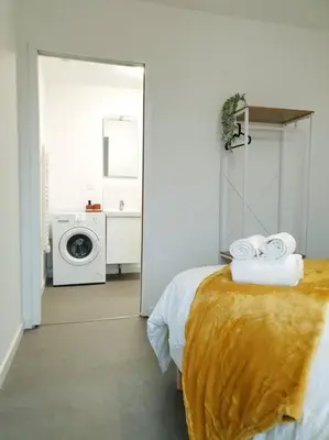 a bathroom with a bed and a washing machine at Le Bohème in Pamiers