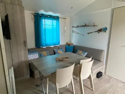 a dining room table and chairs in a room at MH148 camping NOVELA - location entre particuliers-Mobil home 6pl climatisé - in Port-la-Nouvelle