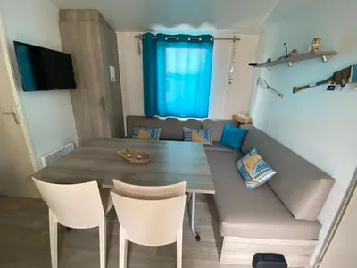 a dining room with a table and chairs and a couch at MH148 camping NOVELA - location entre particuliers-Mobil home 6pl climatisé - in Port-la-Nouvelle