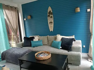 a living room with a couch and a surfboard on a blue wall at Le Sept in Gruissan