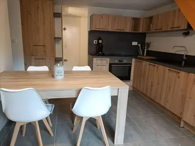 a kitchen with a wooden table and white chairs at Le Sept in Gruissan
