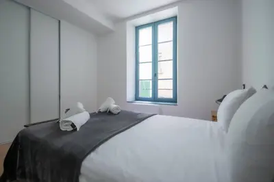 a white bedroom with a large bed with two towels on it at L'As de Carreaux in Narbonne