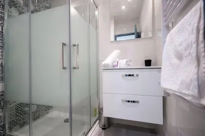 a white bathroom with a shower and a sink at L'As de Carreaux in Narbonne