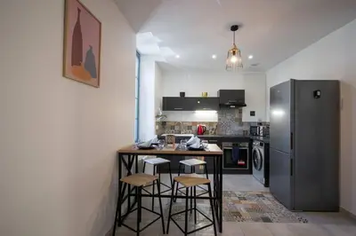 a kitchen with a counter with stools and a refrigerator at L'As de Carreaux in Narbonne