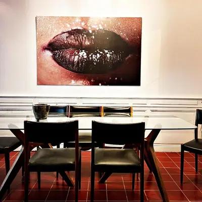 a dining room table with chairs and a painting on the wall at La Paloma La Palme in Lapalme