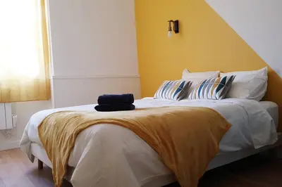 a bedroom with a large bed with a yellow wall at Escapade détente au cœur de Pamiers in Pamiers