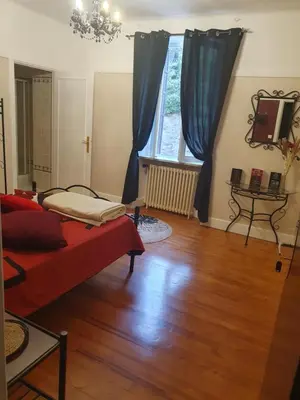 a living room with a bed and a wooden floor at le lorrain in Saint-Pons