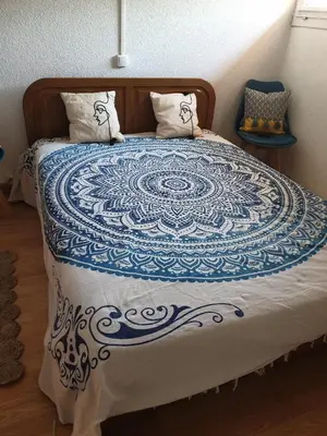 a bed with a blue and white quilt on it at T2 plage place parking in Port-la-Nouvelle