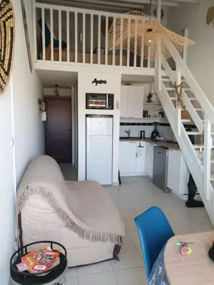 a living room with a staircase and a kitchen at T2 plage place parking in Port-la-Nouvelle