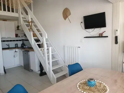 a kitchen and a dining room with a table and a staircase at T2 plage place parking in Port-la-Nouvelle