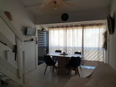 a living room with a table and chairs and a television at T2 plage place parking in Port-la-Nouvelle
