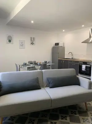a white couch in a room with a kitchen at Appartement cœur de village Numéro2 in Peyriac-de-Mer