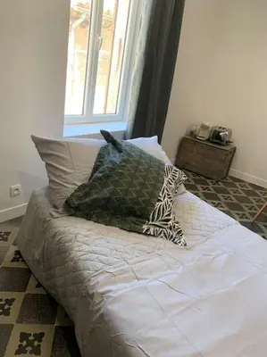 a bed with pillows on it in a room with a window at Appartement cœur de village Numéro2 in Peyriac-de-Mer