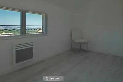 a white room with a chair and two windows at Maison confortable à 10 km des plages de la Méditerranée au bord du village pittoresque in Treilles