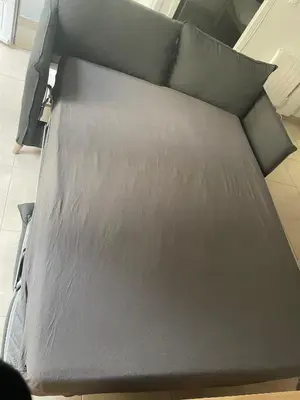a bed with black sheets and pillows on it at Vivez Castelnaudary à pied, T2 cosy avec jardin, proche gare et canal du midi in Castelnaudary