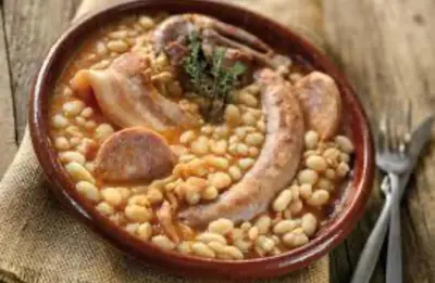 a bowl of food with beans and sausages and meat at Vivez Castelnaudary à pied, T2 cosy avec jardin, proche gare et canal du midi in Castelnaudary